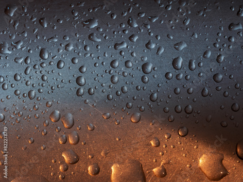Metallfläche mit großen und kleinen Regentropfen, schimmernde Farben photo