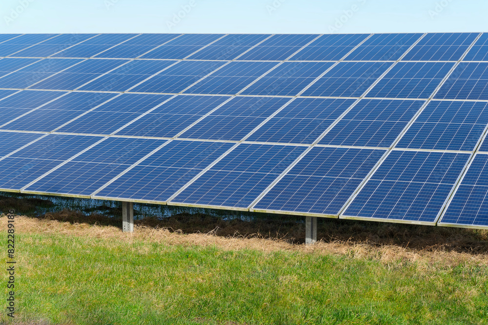 Blue solar cells in a solar panels power farm or photovoltaic cell park in a green field. Green Energy Concept Blue solar cells in a solar panels power farm or photovoltaic cell park in a green field. Green Energy Concept