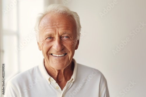 Portrait of a blissful man in his 70s smiling at the camera isolated in light wood minimalistic setup