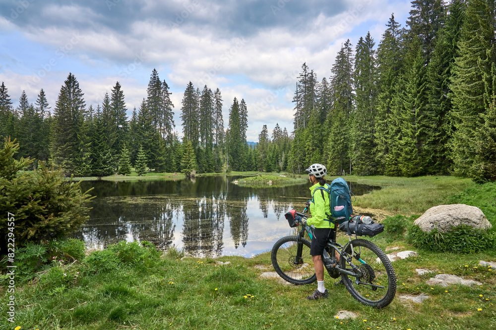 Naklejka premium active senior woman on a bike packing tour with her electric mountain bike in the Bavarian Forest National Park, Bavaria, Germany