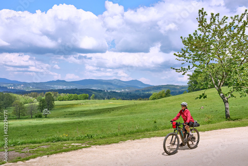 active senior woman on a bike packing tour with her electric mountain bike in the Bavarian Forest near Waldkirchen, Bavaria, Germany