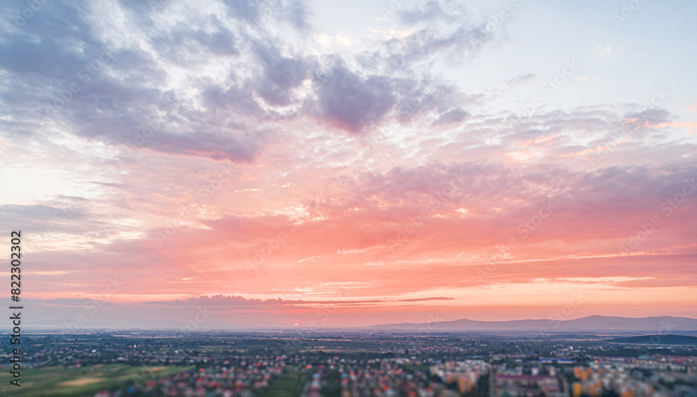 Fototapeta premium Bird's eye view of the sunset. Below are fields and villages against a dramatic, beautiful sky.