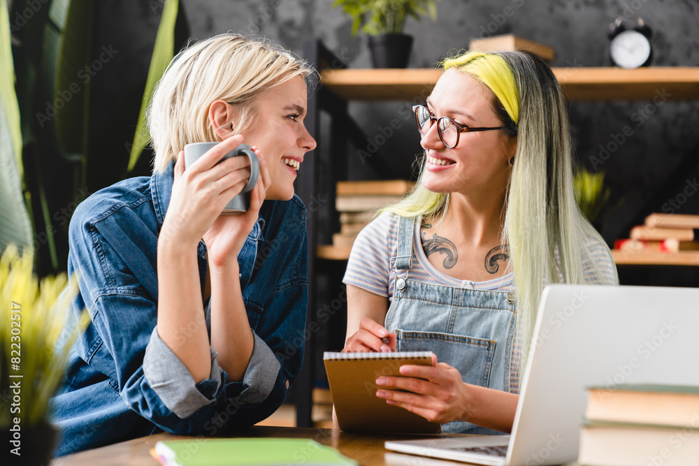 Love and care concept. Romantic relationship between coworkers female lesbian couple lgbtq looking at each other with passion, working together, doing homework paperwork at home office Love and care concept. Romantic relationship between coworkers female lesbian couple lgbtq looking at each other with passion, working together, doing homework paperwork at home office