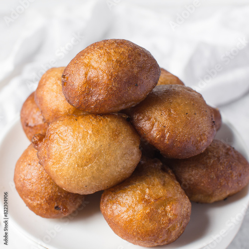 Overhead view of nigerian puff-puff on a white plate, nigerian fried dough balls, flatlay of homemade bofrot on white dish