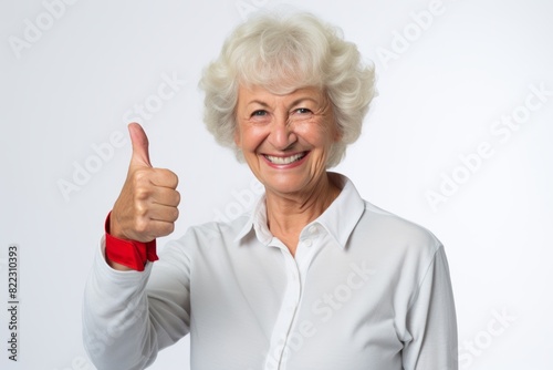 Portrait of a smiling woman in her 50s showing a thumb up isolated on plain white digital canvas