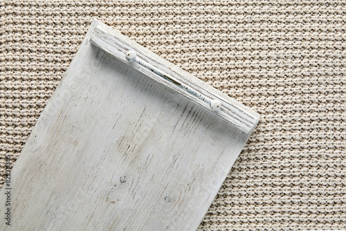Fragment of empty white wooden tray on table covered with beige knitted plaid. Template for displaying food on a menu