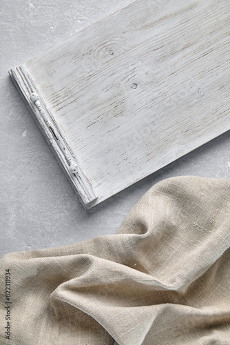 Empty white wooden tray and linen beige kitchen napkin on gray stone table. Template for displaying food on a menu