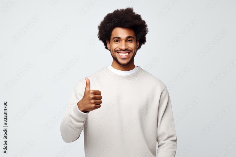 Portrait of a smiling afro-american man in his 20s showing a thumb up over plain white digital canvas Portrait of a smiling afro-american man in his 20s showing a thumb up over plain white digital canvas
