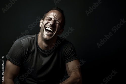 Portrait of a grinning man in his 40s laughing while standing against bare monochromatic room