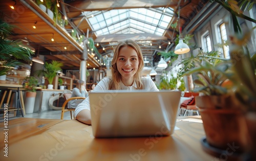 Smiling businesswoman working on a laptop in a brightly lit café