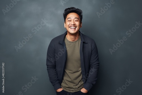Portrait of a joyful asian man in his 30s smiling at the camera over plain cyclorama studio wall © Markus Schröder