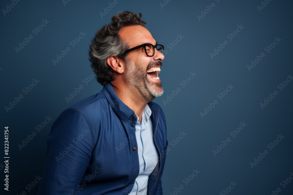 Portrait of a glad man in his 40s laughing while standing against plain cyclorama studio wall