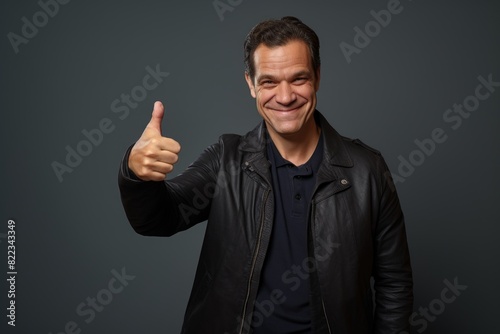 Portrait of a grinning man in his 40s showing a thumb up on plain cyclorama studio wall