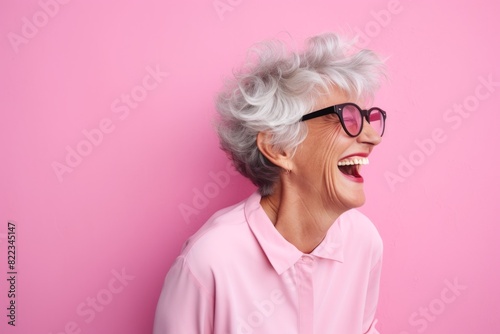 Portrait of a happy woman in her 70s laughing isolated in plain cyclorama studio wall
