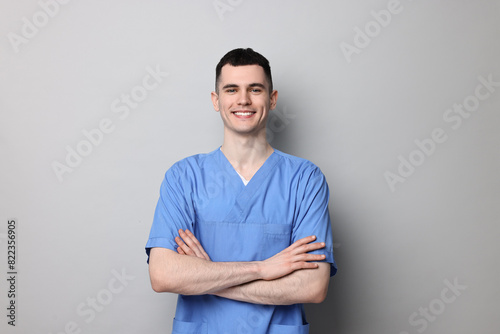 Portrait of smiling medical assistant with crossed arms on grey background