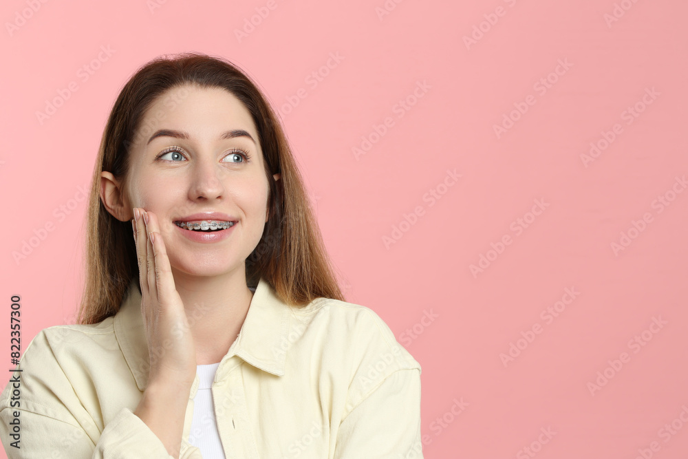 Portrait of smiling woman with dental braces on pink background. Space for text Portrait of smiling woman with dental braces on pink background. Space for text