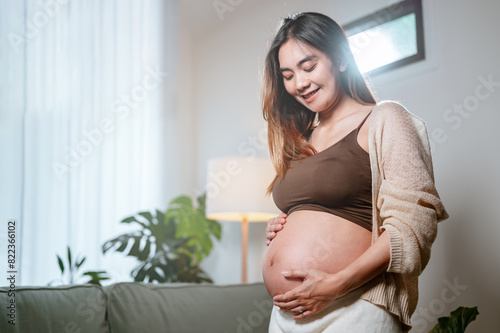 parenthood, pregnancy, family, motherhood, child, baby, pregnant, childbirth, prenatal, healthcare. A woman is pregnant and is smiling. She is wearing a brown top and a white sweater. Free Download parenthood, pregnancy, family, motherhood, child, baby, pregnant, childbirth, prenatal, healthcare. A woman is pregnant and is smiling. She is wearing a brown top and a white sweater. - GFXLoad