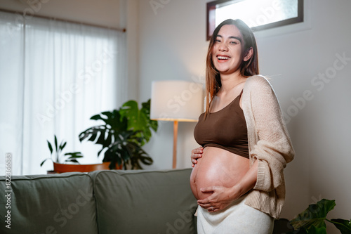 parenthood, pregnancy, family, abdomen, motherhood, maternity, pregnant, parent, birth, prenatal. A woman is smiling and holding her stomach while sitting on a couch. She is pregnant. Free Download parenthood, pregnancy, family, abdomen, motherhood, maternity, pregnant, parent, birth, prenatal. A woman is smiling and holding her stomach while sitting on a couch. She is pregnant. - GFXLoad