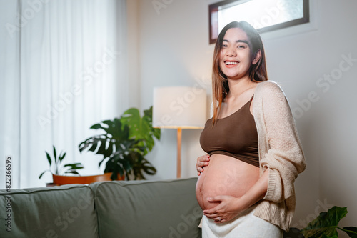 parenthood, pregnancy, family, abdomen, motherhood, maternity, pregnant, parent, birth, prenatal. A woman is smiling and holding her stomach while sitting on a couch. She is pregnant. Free Download parenthood, pregnancy, family, abdomen, motherhood, maternity, pregnant, parent, birth, prenatal. A woman is smiling and holding her stomach while sitting on a couch. She is pregnant. - GFXLoad