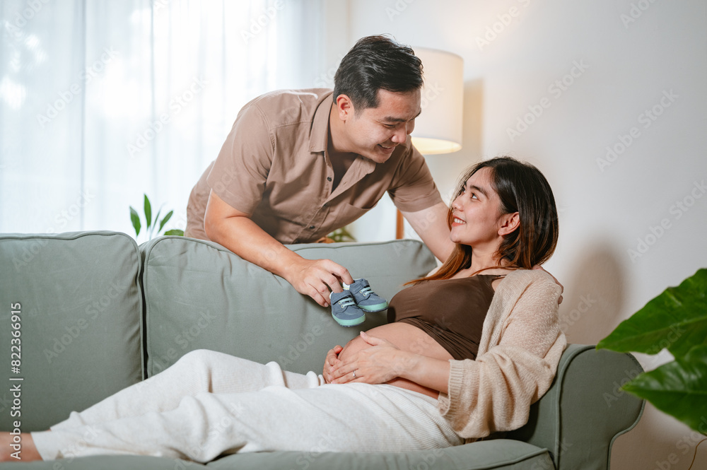 parenthood, pregnancy, motherhood, female, pregnant, father, hugging, parent, husband, together. A man and woman are sitting on couch, with the woman is pregnant. The man is holding baby boot in hand. parenthood, pregnancy, motherhood, female, pregnant, father, hugging, parent, husband, together. A man and woman are sitting on couch, with the woman is pregnant. The man is holding baby boot in hand.