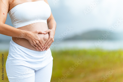 mother, pregnancy, motherhood, anticipation, child, pregnant, birth, human, stomach, health. A woman is holding her stomach possibly to show her pregnancy, with the woman standing in a grassy field.