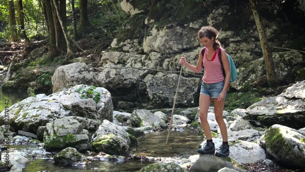 Female Adult Hiker trying To get on the other Side of Forest Water Stream - River Idrija Slovenia Female Adult Hiker trying To get on the other Side of Forest Water Stream - River Idrija Slovenia