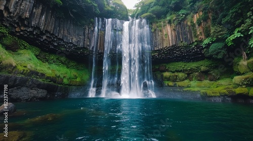 High-angle shot of a majestic waterfall  water flowing rapidly over the rocks into a serene pool below.
