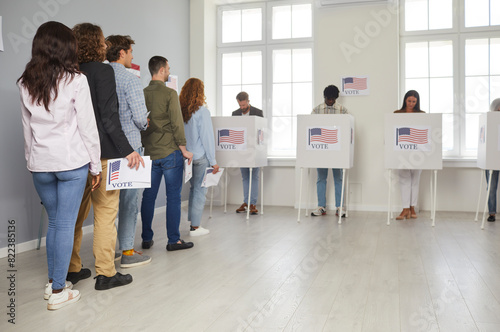 Foto Group of diverse american people voters standing in queue holding ballot paper at electoral center on election day and putting their ballots in bin in voting booth