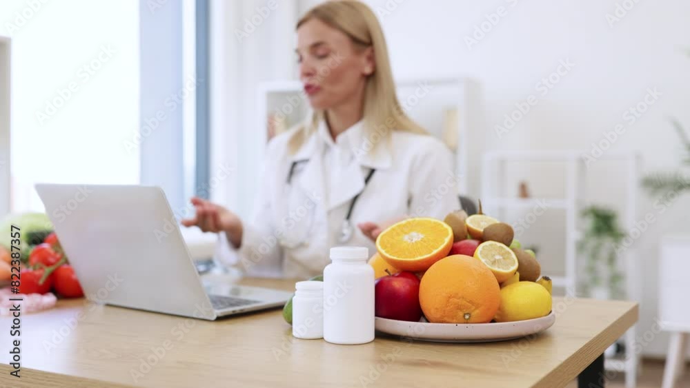 Cropped view of mature female making video call via wireless device at doctor's workplace in hospital. Attentive dietitian providing online consultation about client's progress in identifying foods. Cropped view of mature female making video call via wireless device at doctor's workplace in hospital. Attentive dietitian providing online consultation about client's progress in identifying foods.