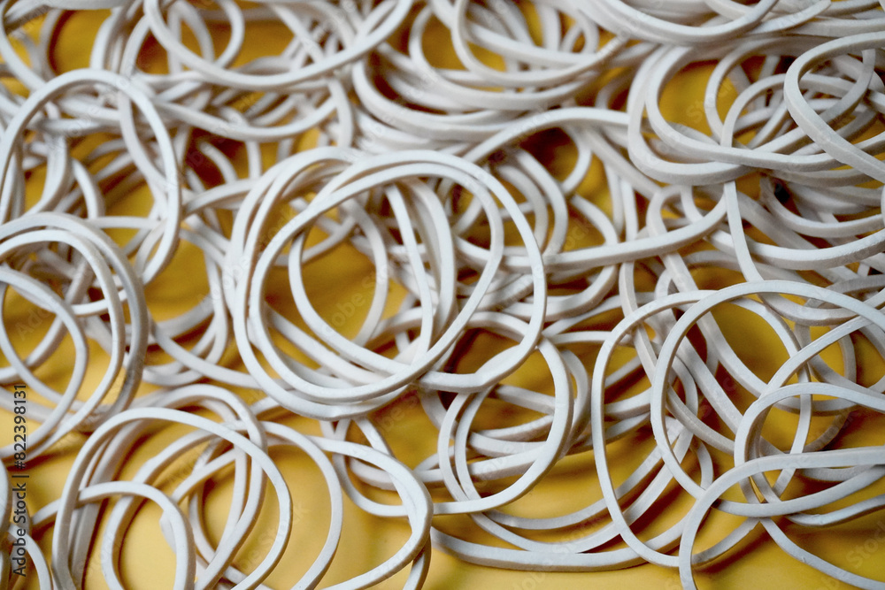 white rubber band pile on a yellow background, close up view white rubber band pile on a yellow background, close up view