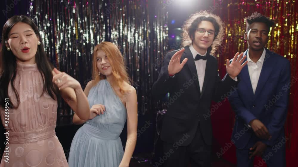 Four well-dressed dynamic teenagers in classy suits and evening gowns dancing and singing at prom party while enjoying prom party in the night club after graduation ceremony Four well-dressed dynamic teenagers in classy suits and evening gowns dancing and singing at prom party while enjoying prom party in the night club after graduation ceremony