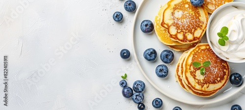 Brunch Delight A delightful brunch setting featuring cottage cheese pancakes served with a side of sour cream and a generous sprinkle of fresh blueberries,  photo