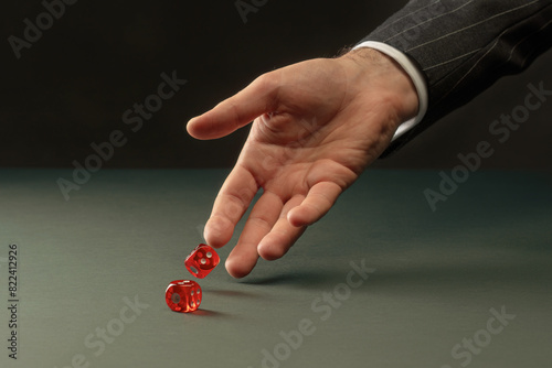 Man's hand throws red dice. Male hand rolls red dices on table. Concept of Casino game and luck. Toned image