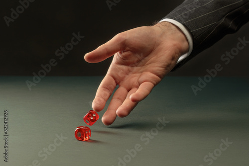 Man's hand throws red dice. Male hand rolls red dices on table. Concept of Casino game and luck. Toned image