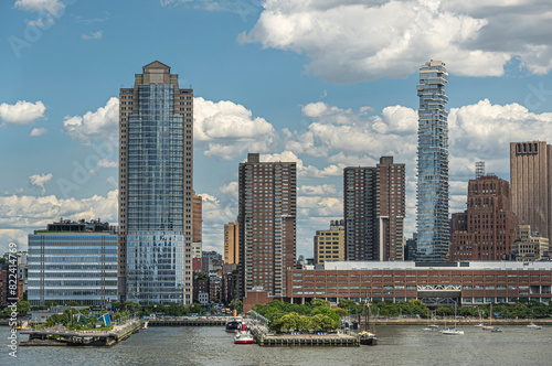 New York, NY, USA - August 1, 2023: City Headquarters building and 56 Leonard street skyscraper seen from Hudson river under blue cloudscape. Looking straight into N. Moore Street. Green tree line, pi