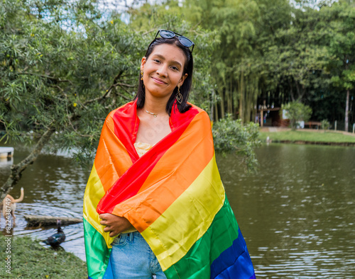 joven lesbiana hispano latina mirando la cámara feliz con la bandera del orgullo gay  photo