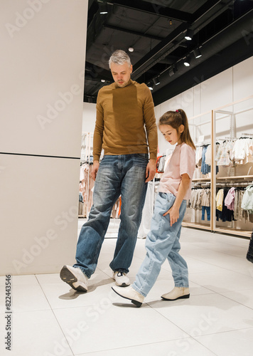Father and Daughter Try on Shoes Together in Brightly Lit Clothing Store During a Weekend Afternoon