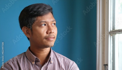 An Indian 25 years old men with a thinking expression on his face in front of the plain blue background