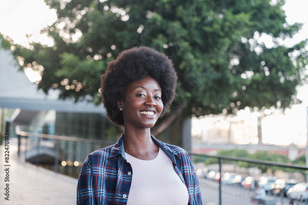 Portrait of student with afro hair smiling and walking around the faculty after leaving university Portrait of student with afro hair smiling and walking around the faculty after leaving university