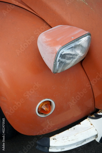 Bild auf Leinwand Kotflügel und Scheinwerfer in Orange mit Rost und Patina eines französischen Kle