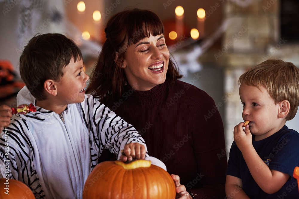Fototapeta premium Happy family, mother and kids with pumpkin for halloween to celebrate with siblings, candy or smile. Home, mom or parent with children eating sweets in vegetable for holiday, decoration and party
