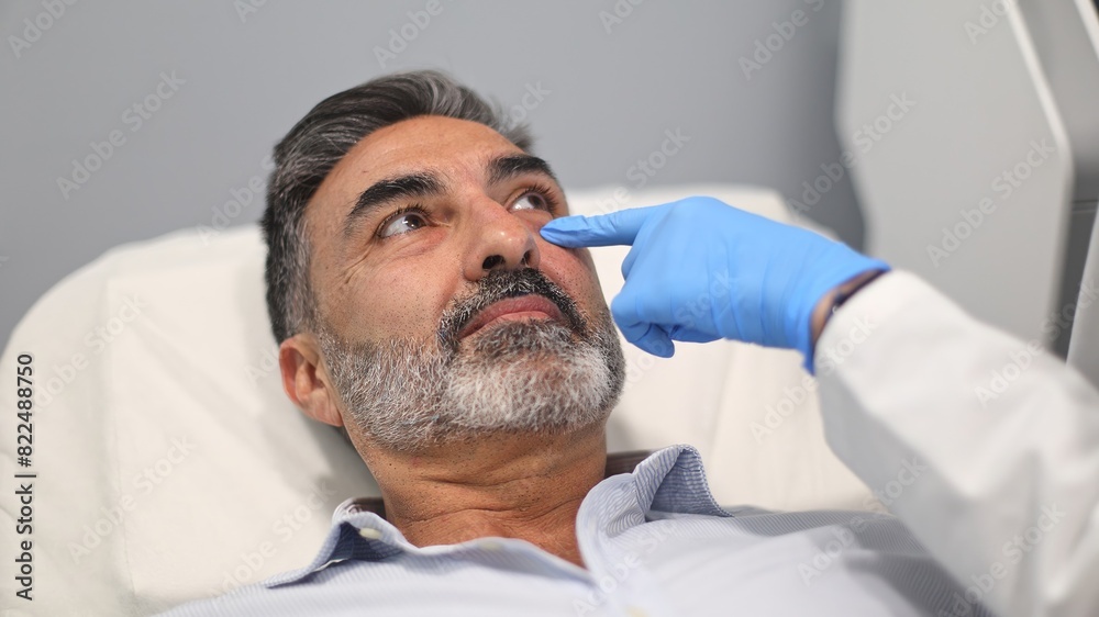 Doctor closely examining a male patient's face before a cosmetic procedure at a beauty clinic Doctor closely examining a male patient's face before a cosmetic procedure at a beauty clinic