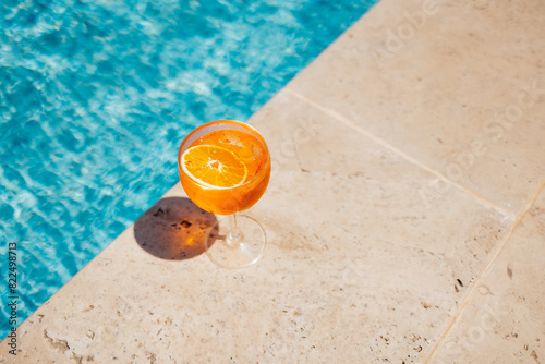 Glass of spritz aperol with orange slice against poolside at resort hotel during vacation. photo