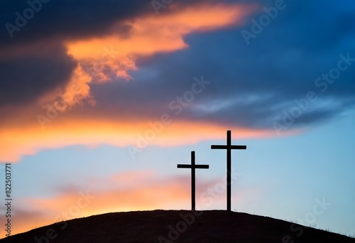 Three crosses on a hill against a dramatic sunset sky with orange and blue clouds