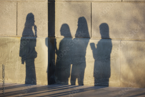 Shadows of people on building wall. Group of women talking on city street