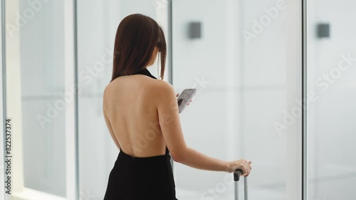 Business, stylish girl, woman in black clothes holds a phone in her hands, looks at social networks, Internet, business lady, airport terminal, Dubai, luxury and money, Emirates, success, confidence
