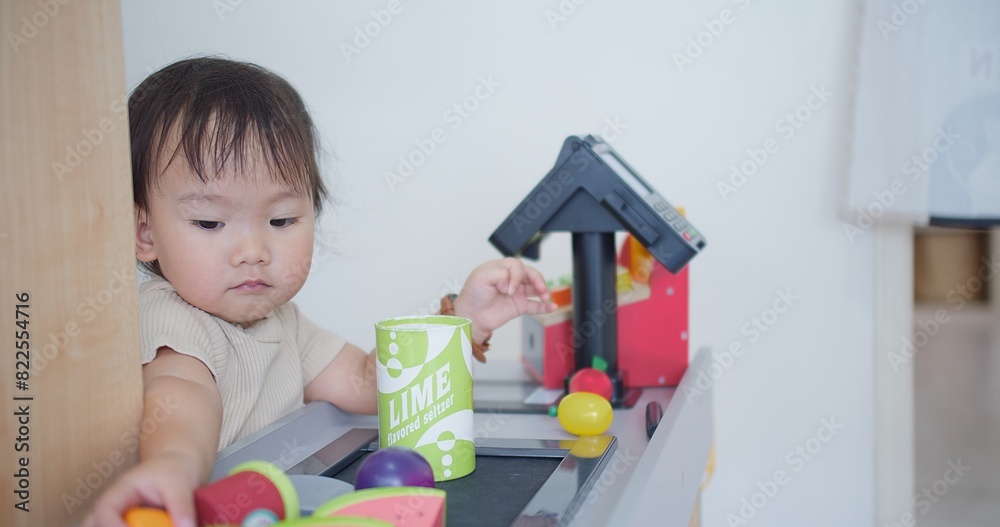 A young child is playing with a toy kitchen set, including a toy toaster and a toy shopping bag A young child is playing with a toy kitchen set, including a toy toaster and a toy shopping bag