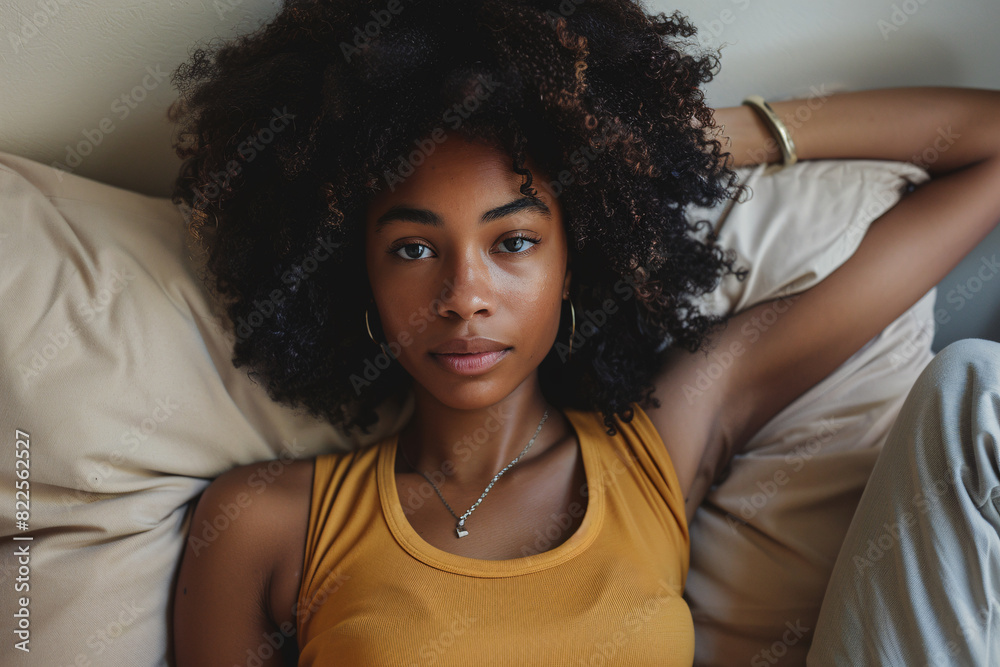 A beautiful young black woman lying on a beige sofa A beautiful young black woman lying on a beige sofa