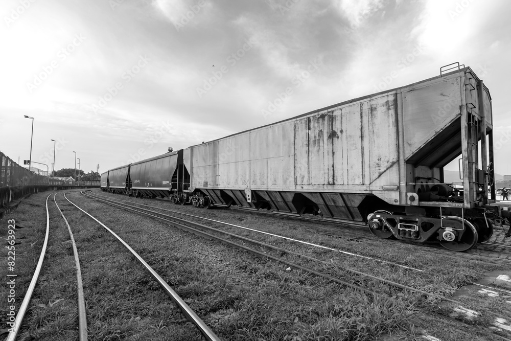 Freight train passing through the Porto railway. Grain export terminals. City of Santos, Brazil. Black and white image. Freight train passing through the Porto railway. Grain export terminals. City of Santos, Brazil. Black and white image.