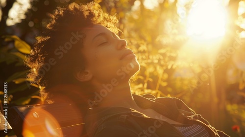 A person sitting on a bench in their garden eyes closed and face turned toward the sun soaking up its warmth and nourishment. photo